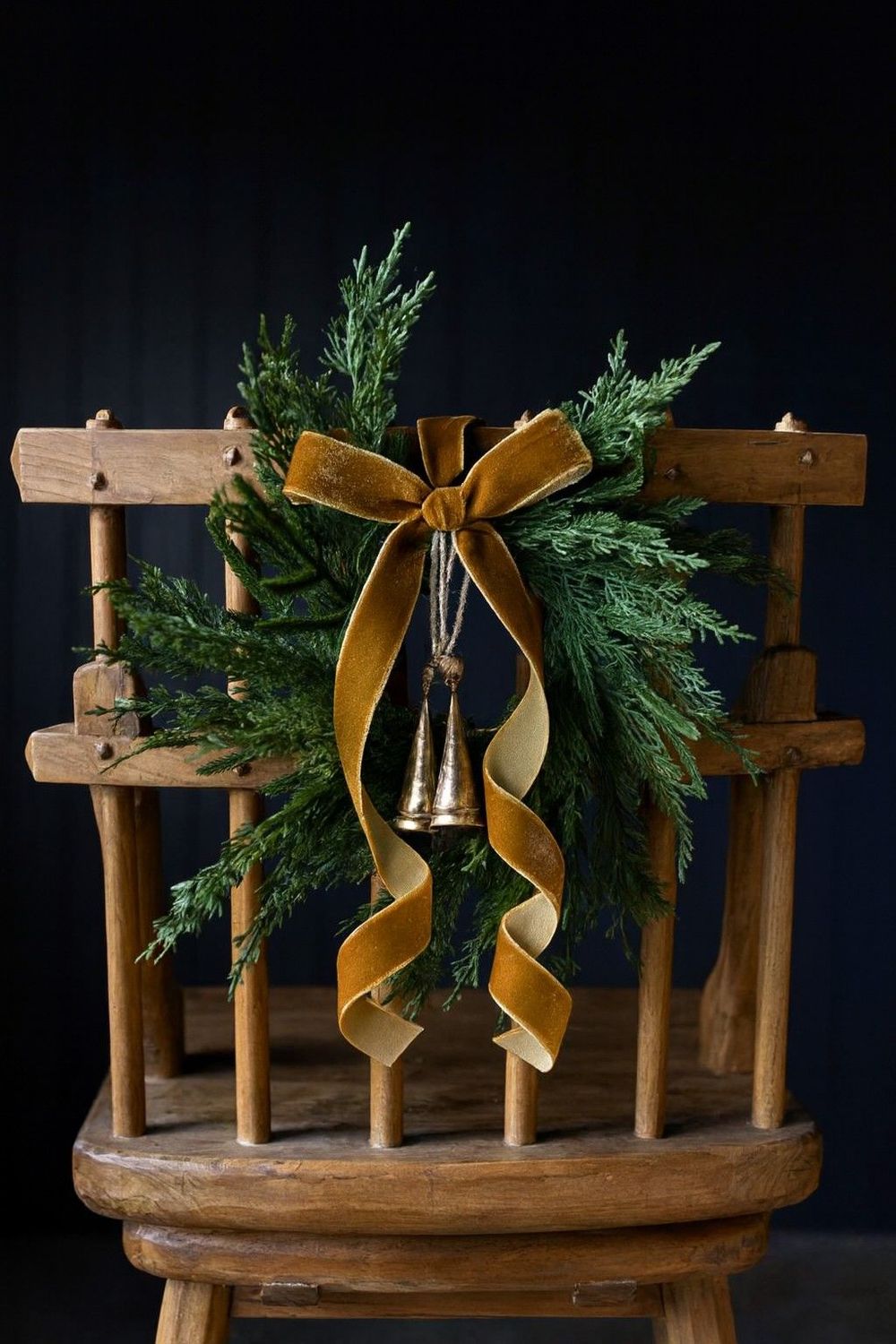 Cypress & Norfolk Pine Real Touch Mini Wreath Antique rustic ladder back chair decorated with Cypress Norfolk Pine Faux wreath and velvet copper ribbon and bells