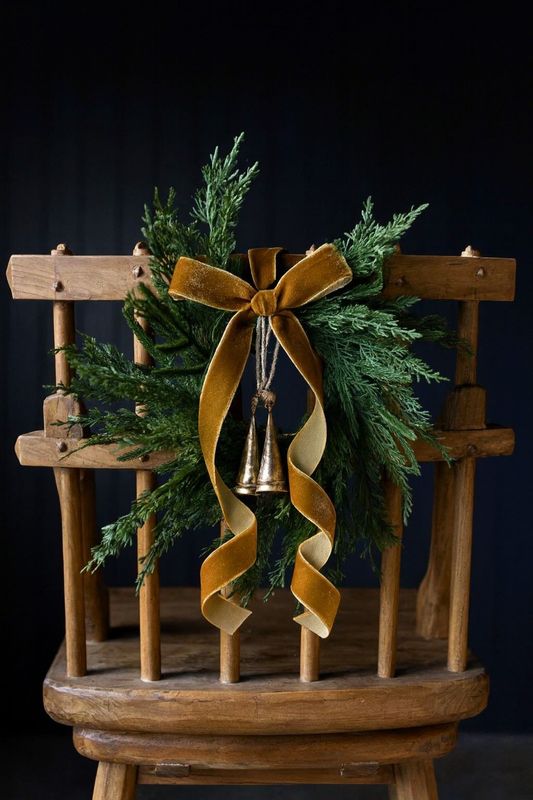 Antique rustic ladder back chair decorated with Cypress Norfolk Pine Faux wreath and velvet copper ribbon and bells