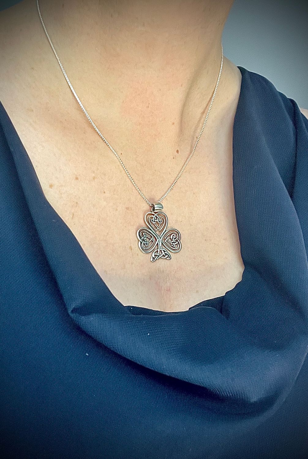 Celtic knot shamrock necklace in sterling silver, handcrafted Irish jewelry with traditional symbolism, shown on model. 