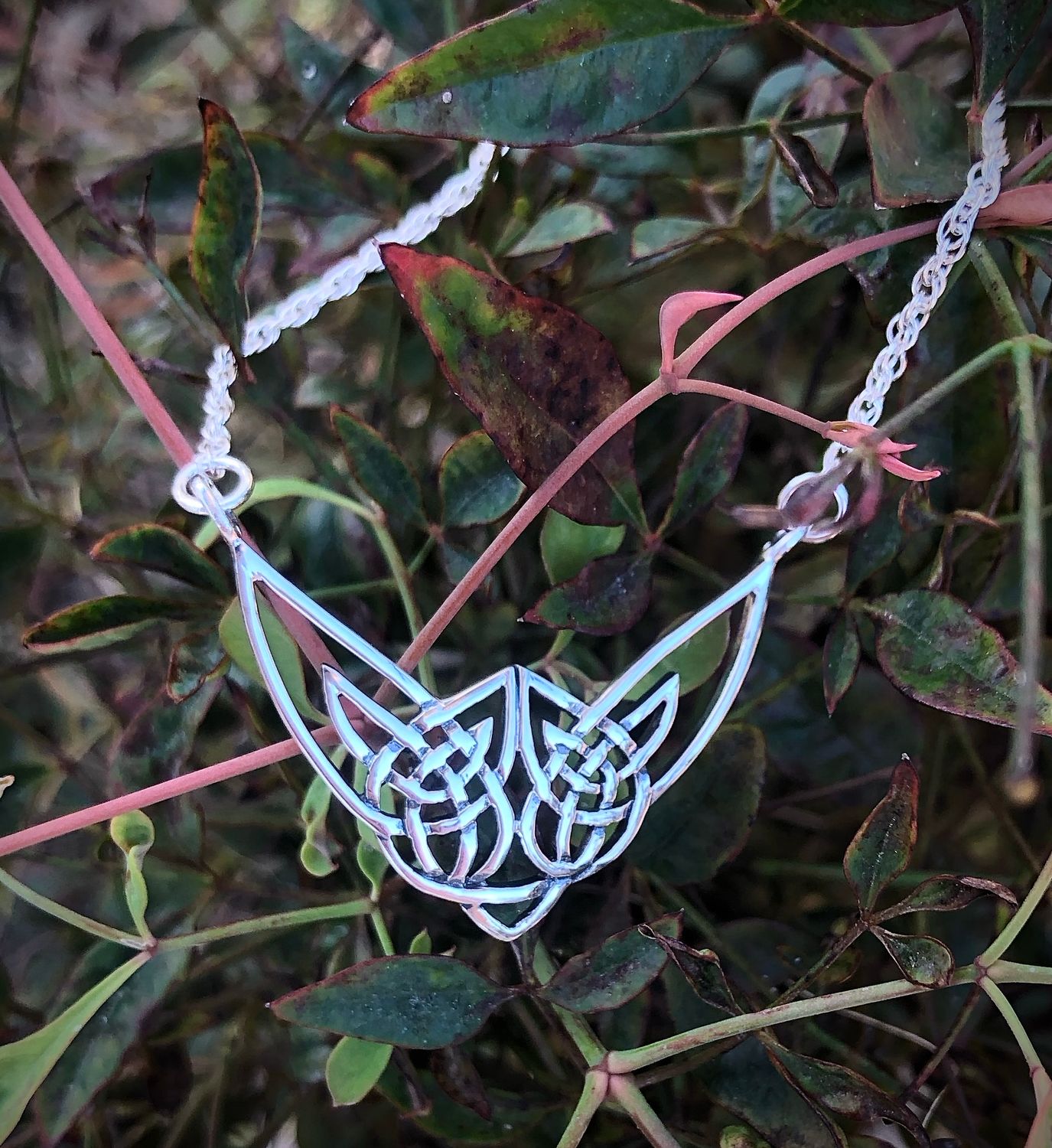 Scottish Highland Cow sterling silver necklet, handcrafted jewelry from Scotland, shown by plants. 