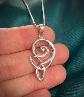 Trinity Knot Swirl Pendant Sterling silver Trinity Knot necklace with swirl, Celtic-inspired jewelry for women’s gifting, held in model's hand.