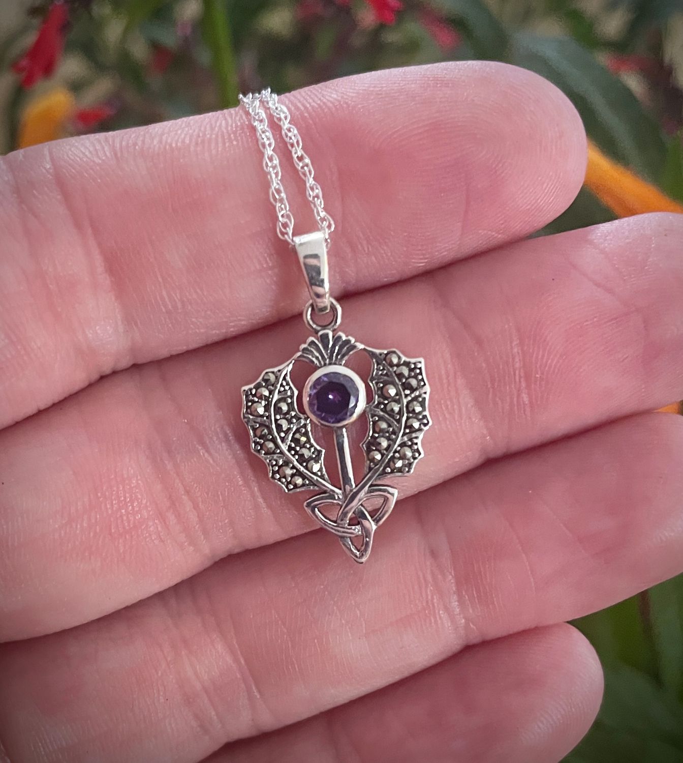 Handcrafted silver pendant with Scottish thistle design, accented with a central Trinity Knot and marcasite stone. 