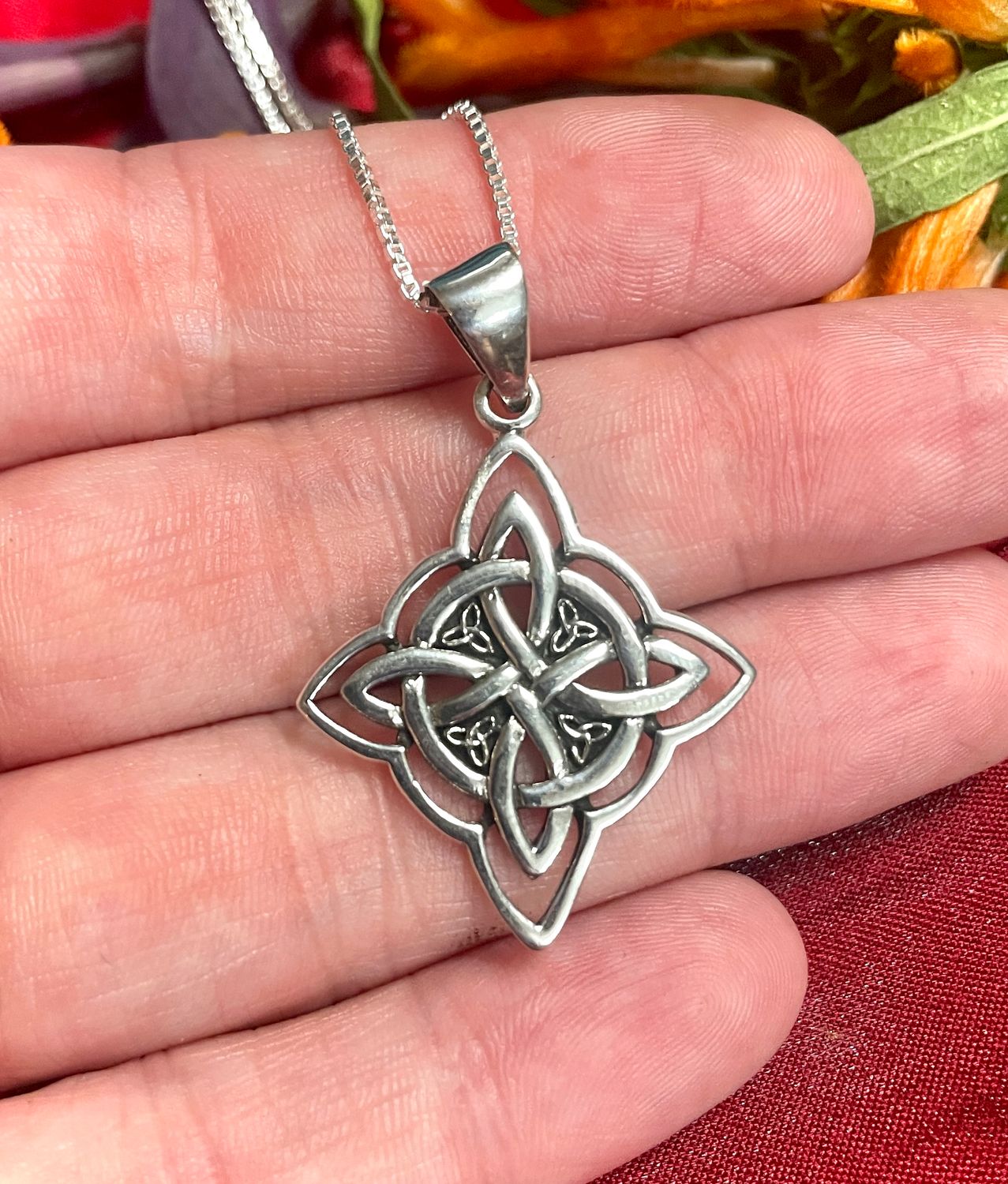 Sterling Silver Witch's Knot Hexefus pendant, held by hand, with 4 small trinity knots.
