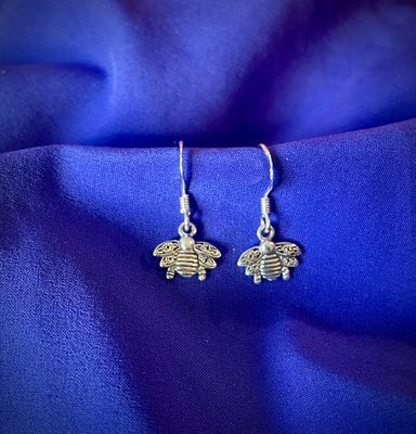 Irish Celtic bee earrings in sterling silver, inspired by Outlander and Celtic traditions, shown on purple fabric.