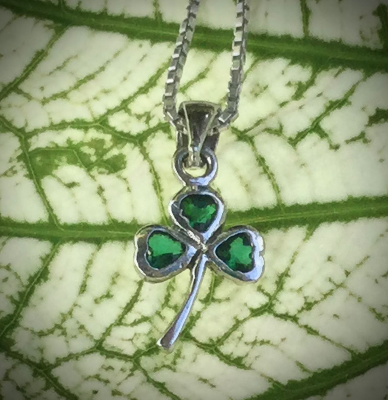 Sterling silver Irish shamrock pendant with green stone, celebrating Irish heritage and tradition, shown by green leaf. 
