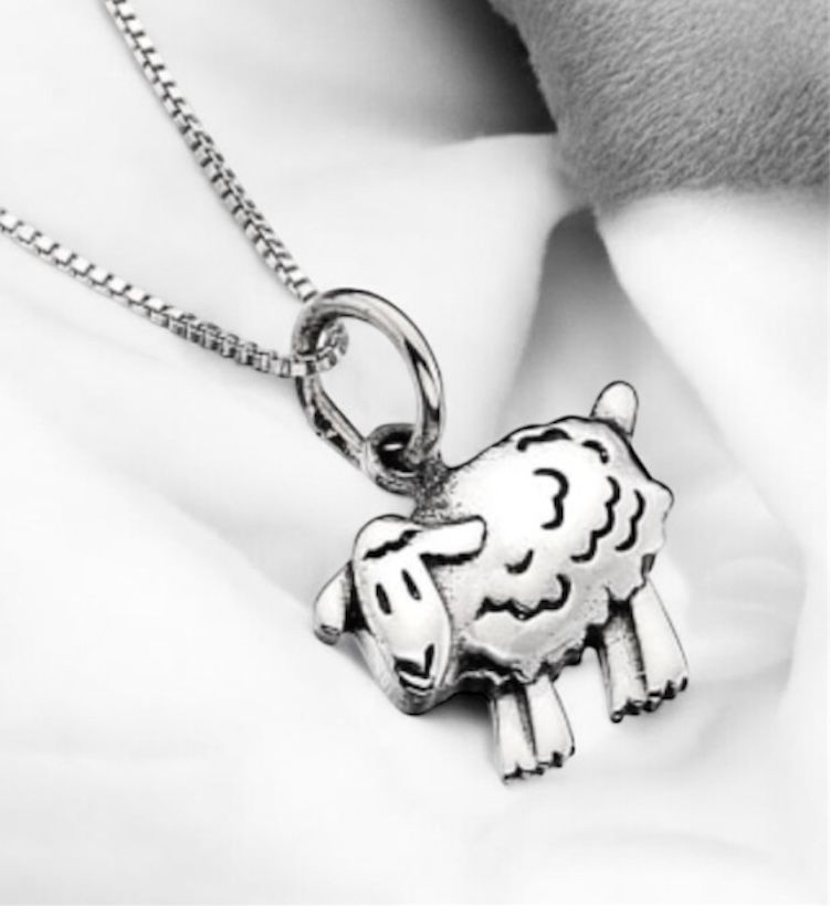 Sterling Silver Sheep Pendant Necklace on white fabric.