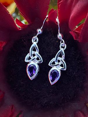 Sterling silver Trinity Knot earrings featuring an amethyst-colored gemstone, celebrating Celtic tradition.
