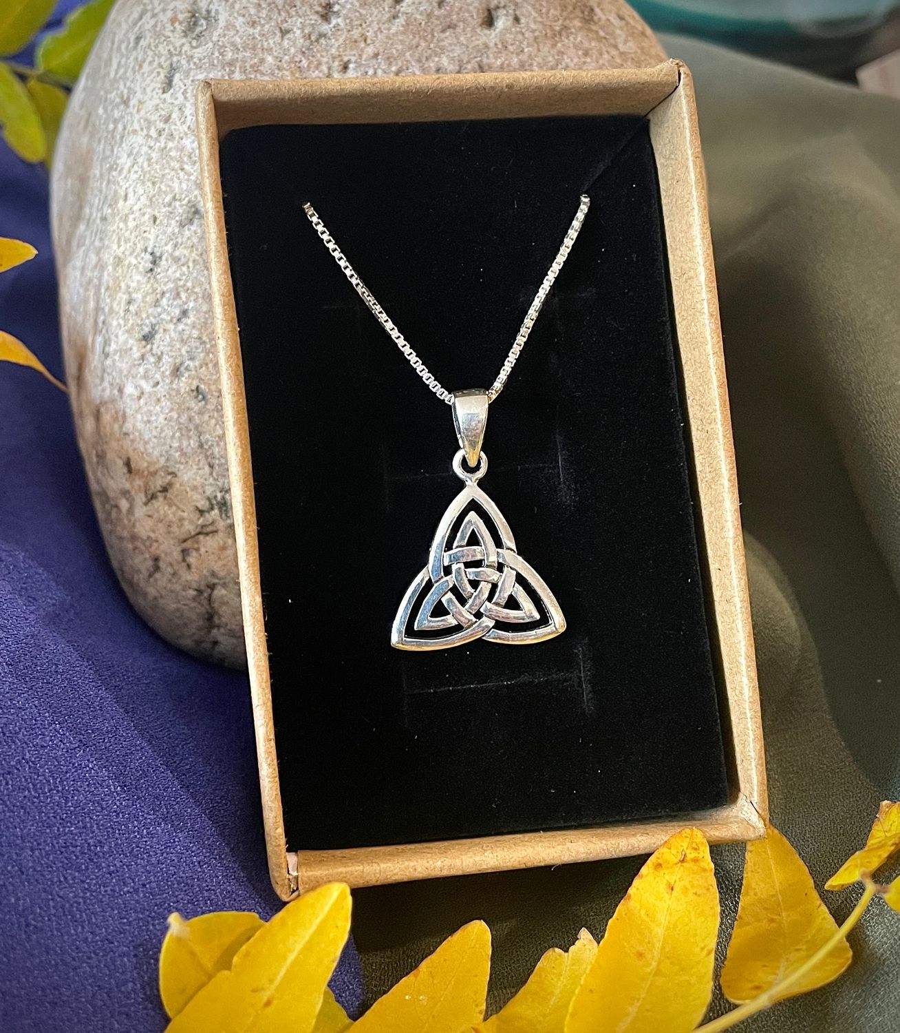 Sterling silver Celtic triquetra pendant necklace with intricate three-loop knot design, shown in jewelry box. 