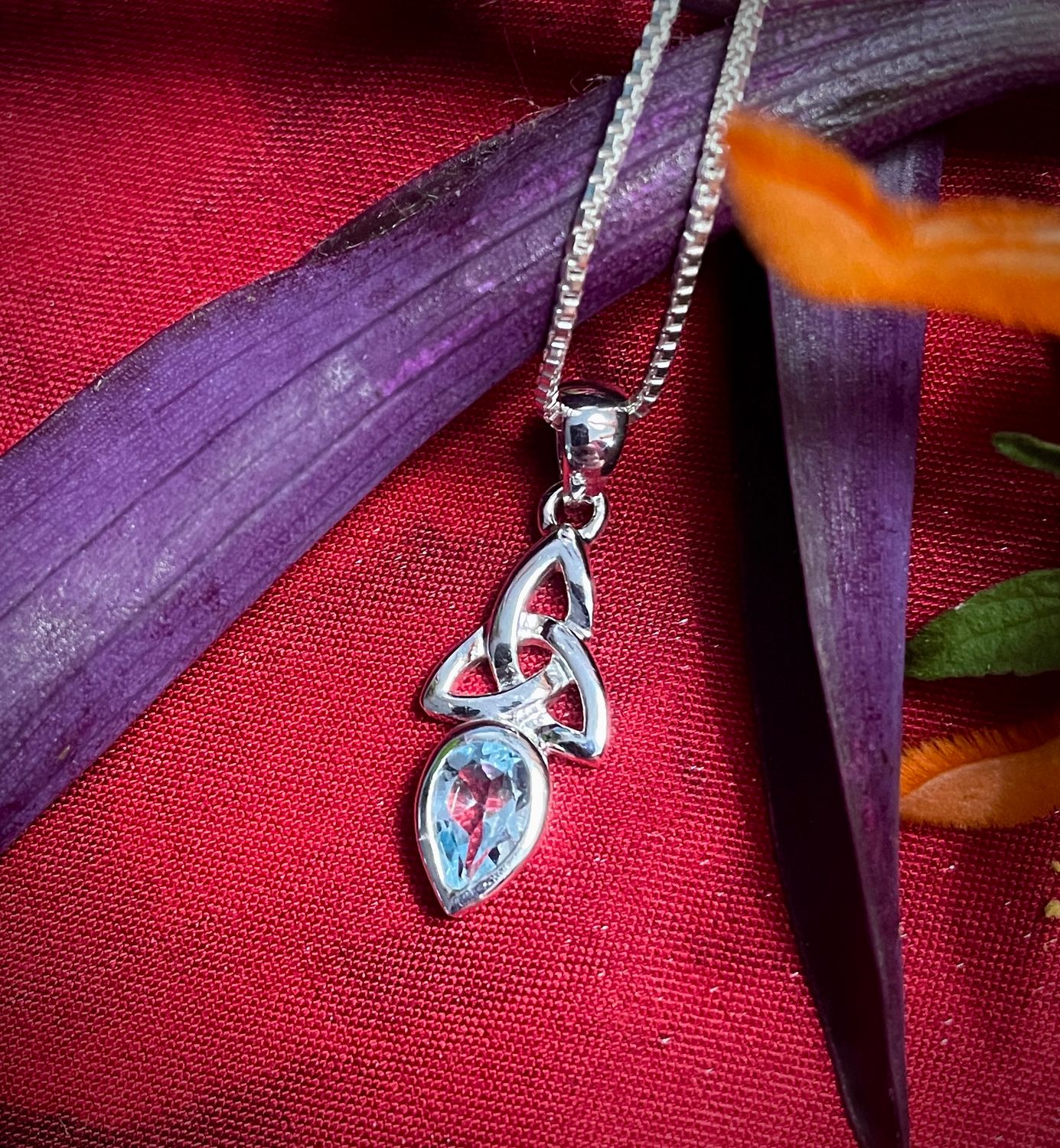 Sterling silver Trinity Knot pendant with blue topaz birthstone, Celtic jewelry symbolizing faith and unity.