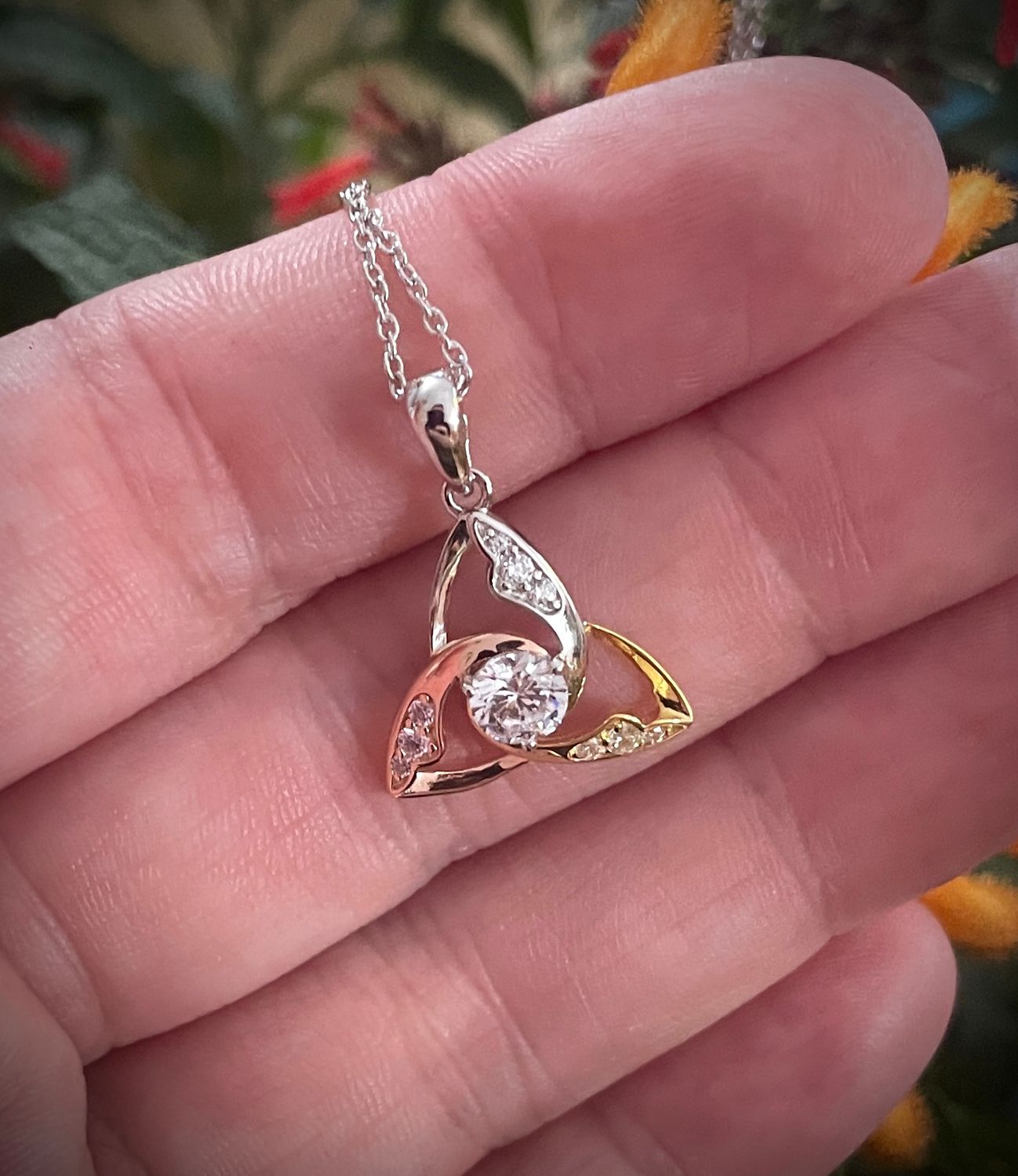 Tri-Color Trinity Pendant with Central CZ Gemstones Tri-color Trinity Knot Celtic pendant in sterling silver with rose and yellow gold plating and central CZ stone, on hand.