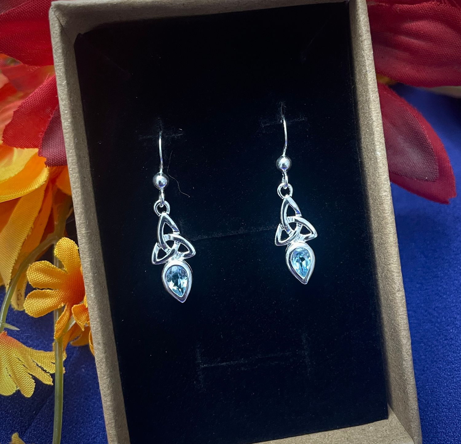 Celtic Trinity Knot silver earrings featuring blue topaz stones, elegant December birthstone jewelry, in jewelry box.