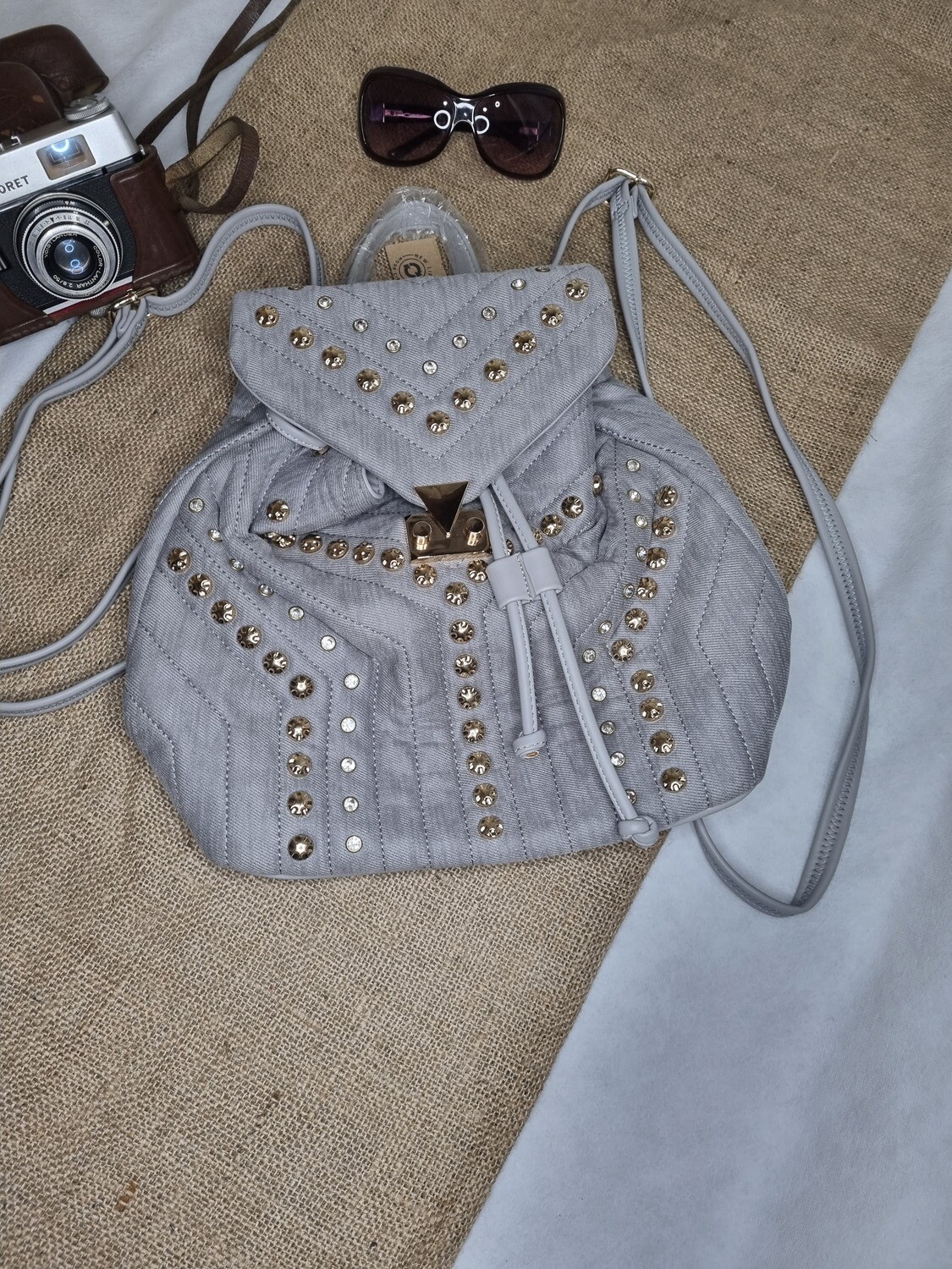 MOCHILA GRIS CON PEDRERIA Y TACHAS.