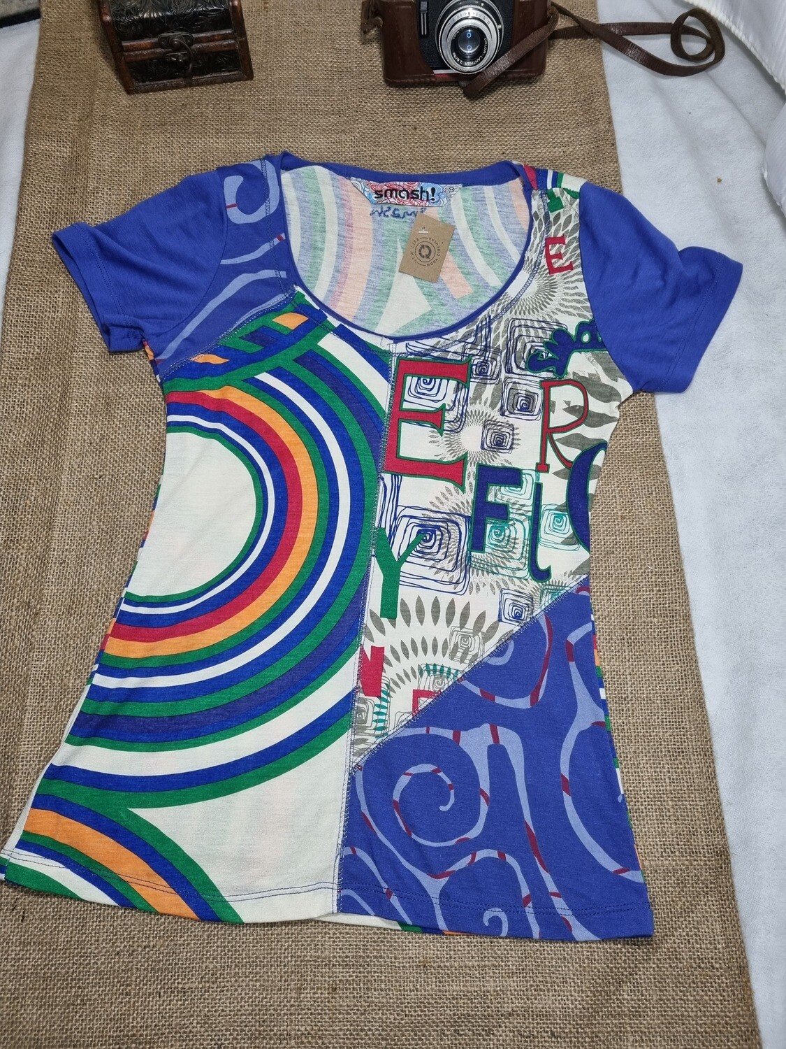 REMERA DE ALGODÓN, MANGA CORTA, CON DISEÑOS GEOMÉTRICOS Y CUELLO REDONDO BAJO. MARCA SMASH!, TALLE XS. NUEVA SIN USO