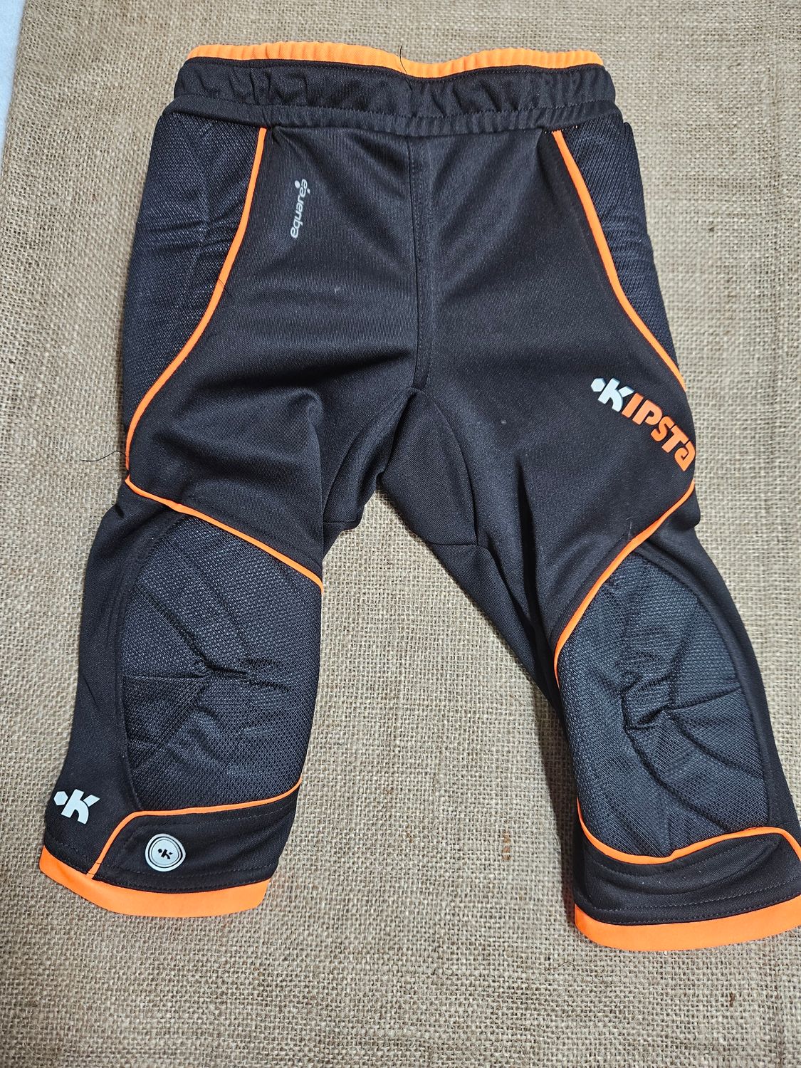 CALZA CORTA DE ARQUERO, PARA NIÑO, CON PROTECCIÓN CADERA Y RODILLAS. TALLE 6. MARCA KIPSTA. IGUAL A NUEVO