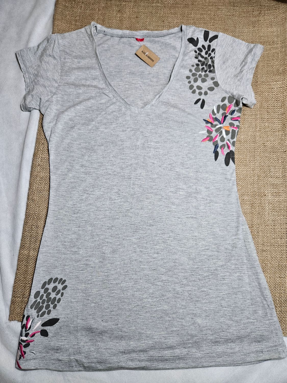 REMERA DE ALGODÓN PARA DAMA, MANGA CORTA, CON BORDADOS EN COSTADO Y ABAJO. COLOR GRIS. CON ESCOTE EN V. TALLE M/L.