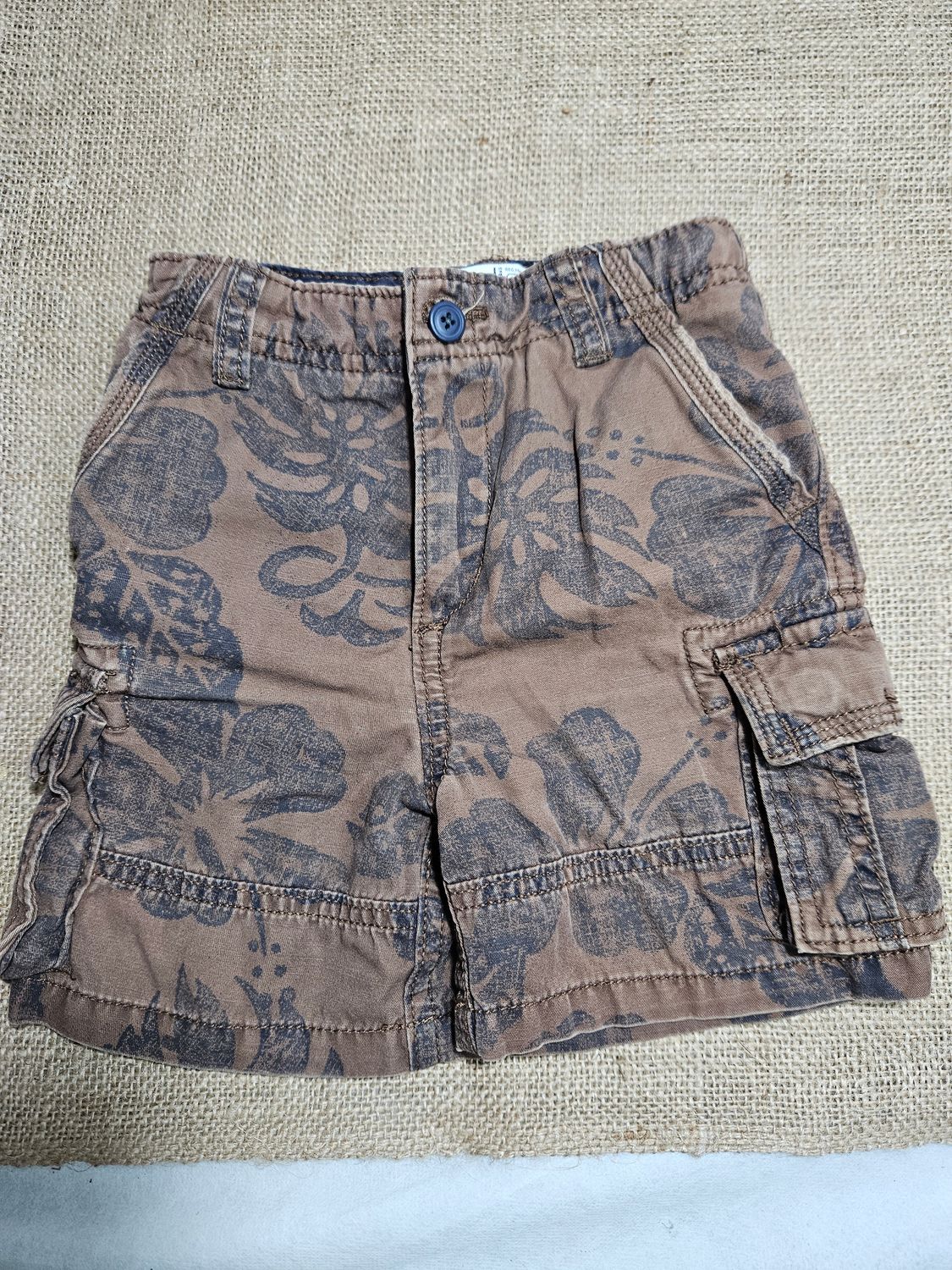 SHORT BERMUDA PARA NIÑO, ESTILO CARGO, MARRON CON ESTAMPA DE OJAS. TALLE 24 MESES. MARCA PLACE. CON USO
