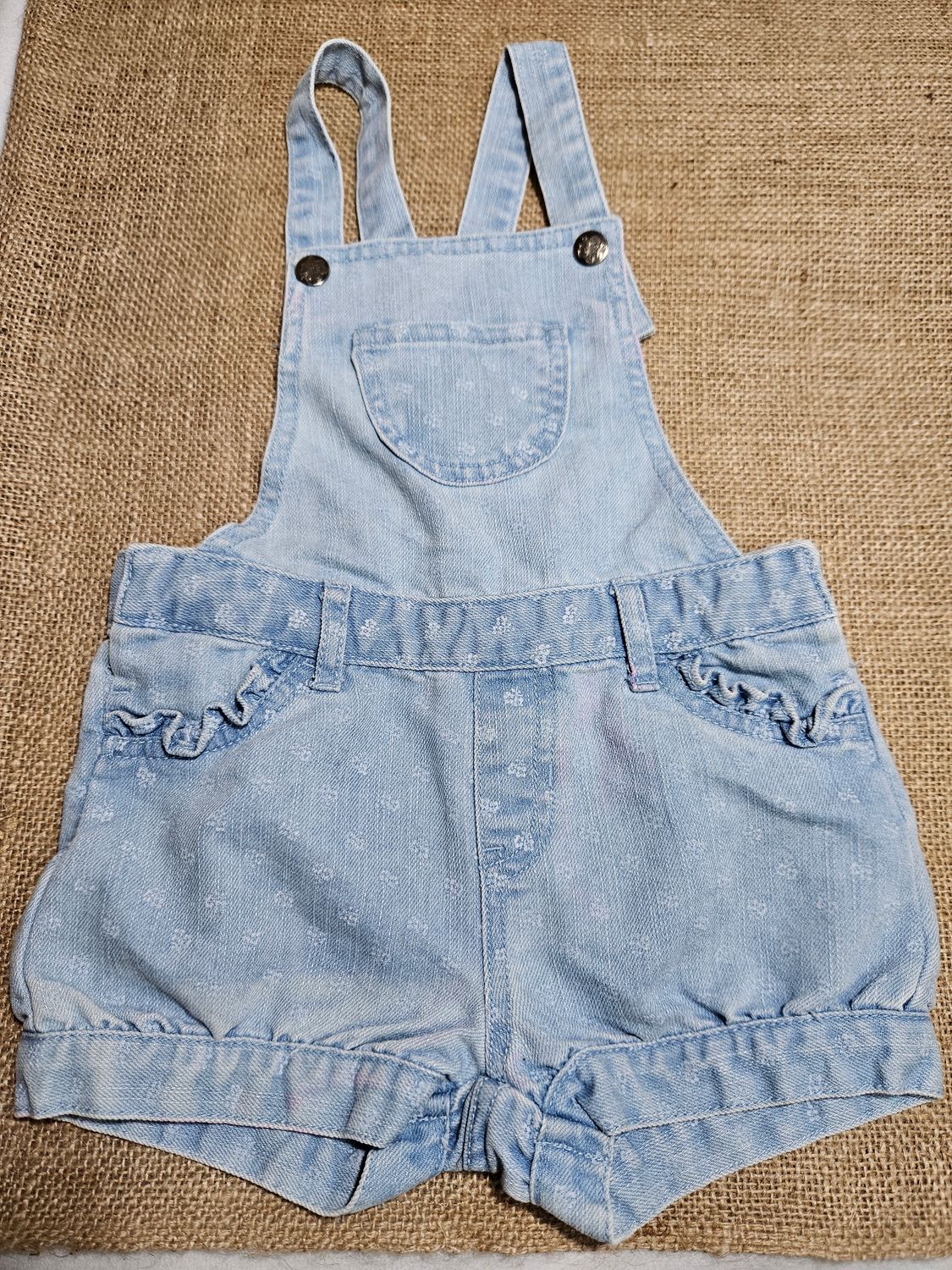 ENTERITO DE JEAN PARA NIÑA, CON VOLADOS EN BOLSILLOS. TIENE UNA PEQUEÑA MANCHA ROSADA EN EL FRENTE. TALLE 3