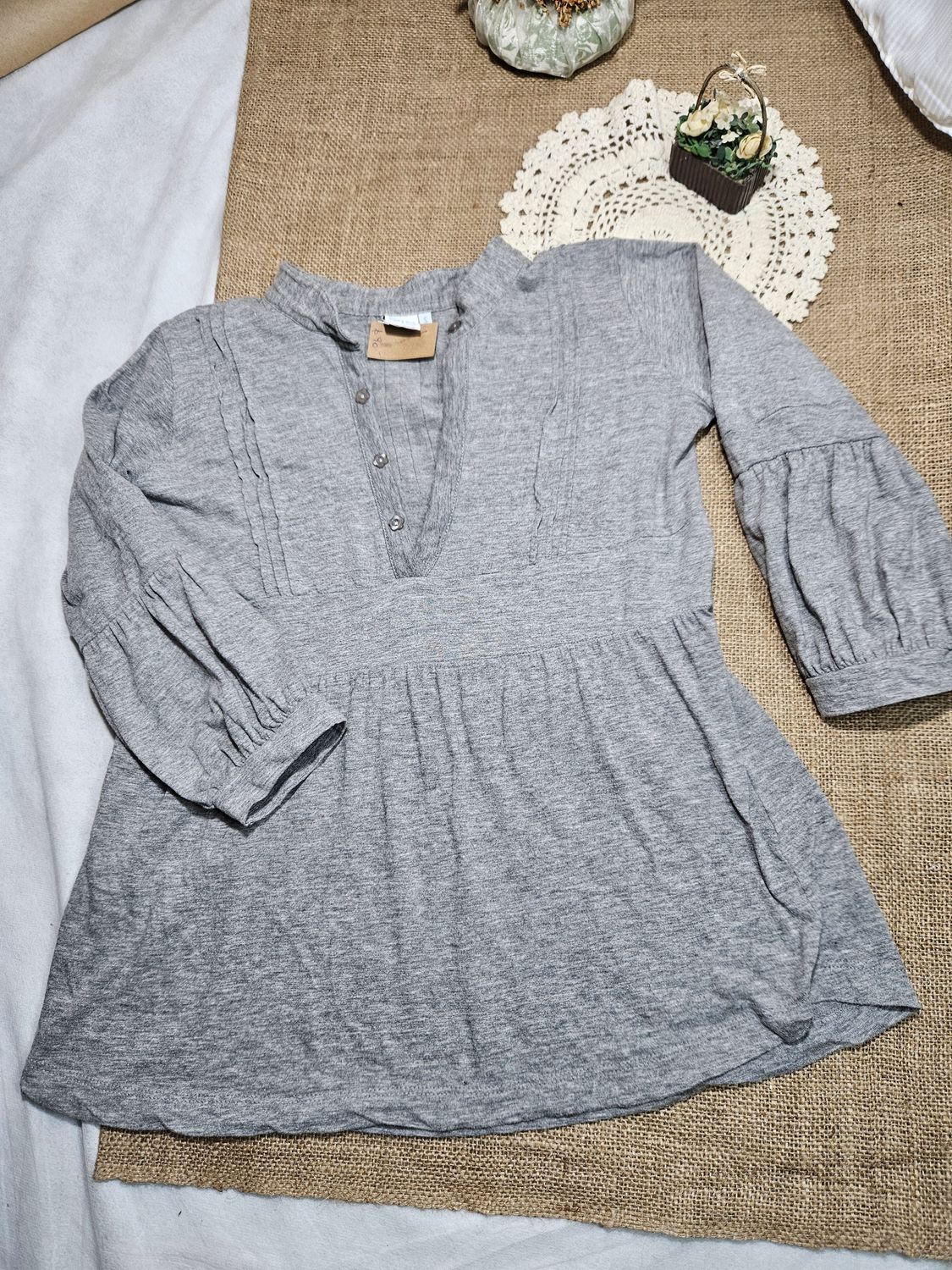 REMERA PARA DAMA, COLOR GRIS, MANGA 3/4 ABUCHONADAS. CUELLO CON BOTONES, Y CORTE EN CINTURA. TALLE S