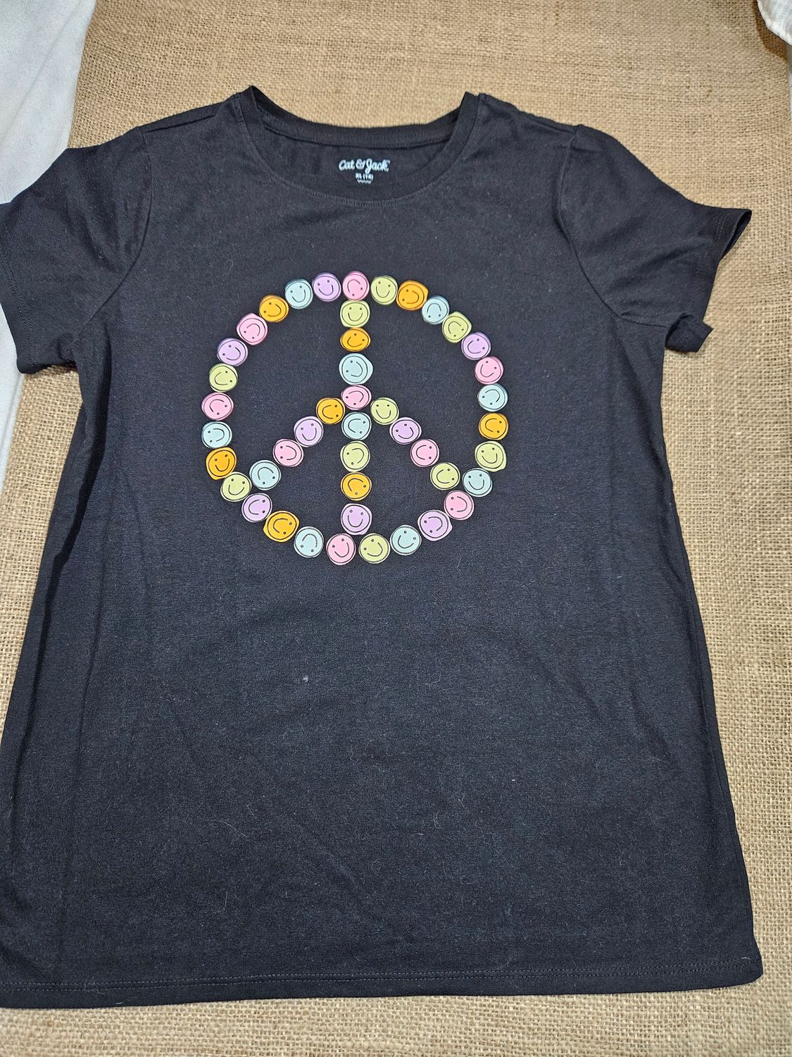 REMERA DE ALGODÓN, PARA NIÑA, MANGA CORTA. COLOR NEGRO, CON ESTAMPA DE SMILES SIGNO DE PAZ EN COLORES. TALLE 14. IGUAL A NUEVA