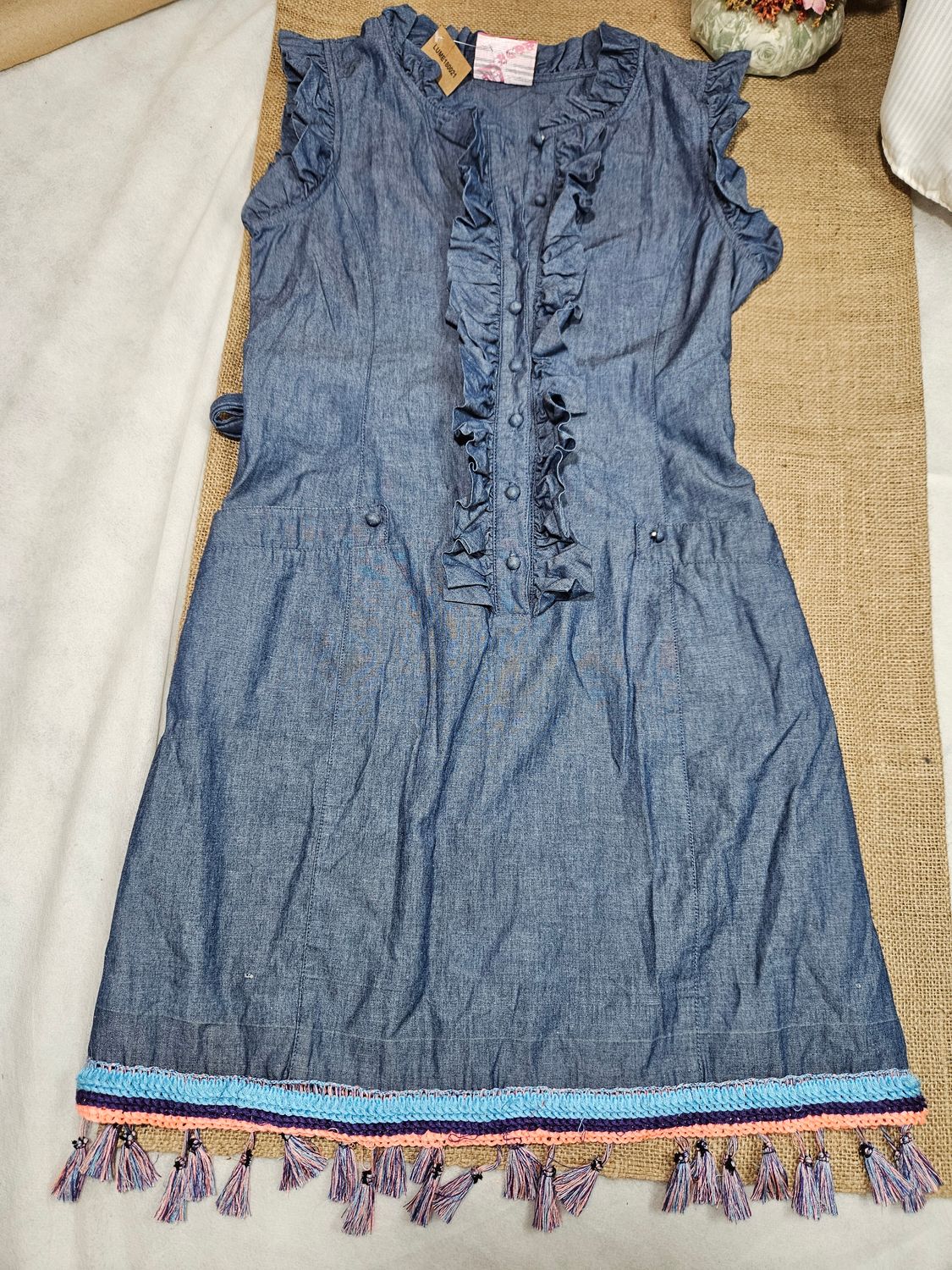 VESTIDO DE JEAN, CON VOLADO EN EL FRENTE, BOLSILLOS Y GUARDA EN HILO DE COLORES. LAZO EN CINTURA. TALLE S AMPLIO