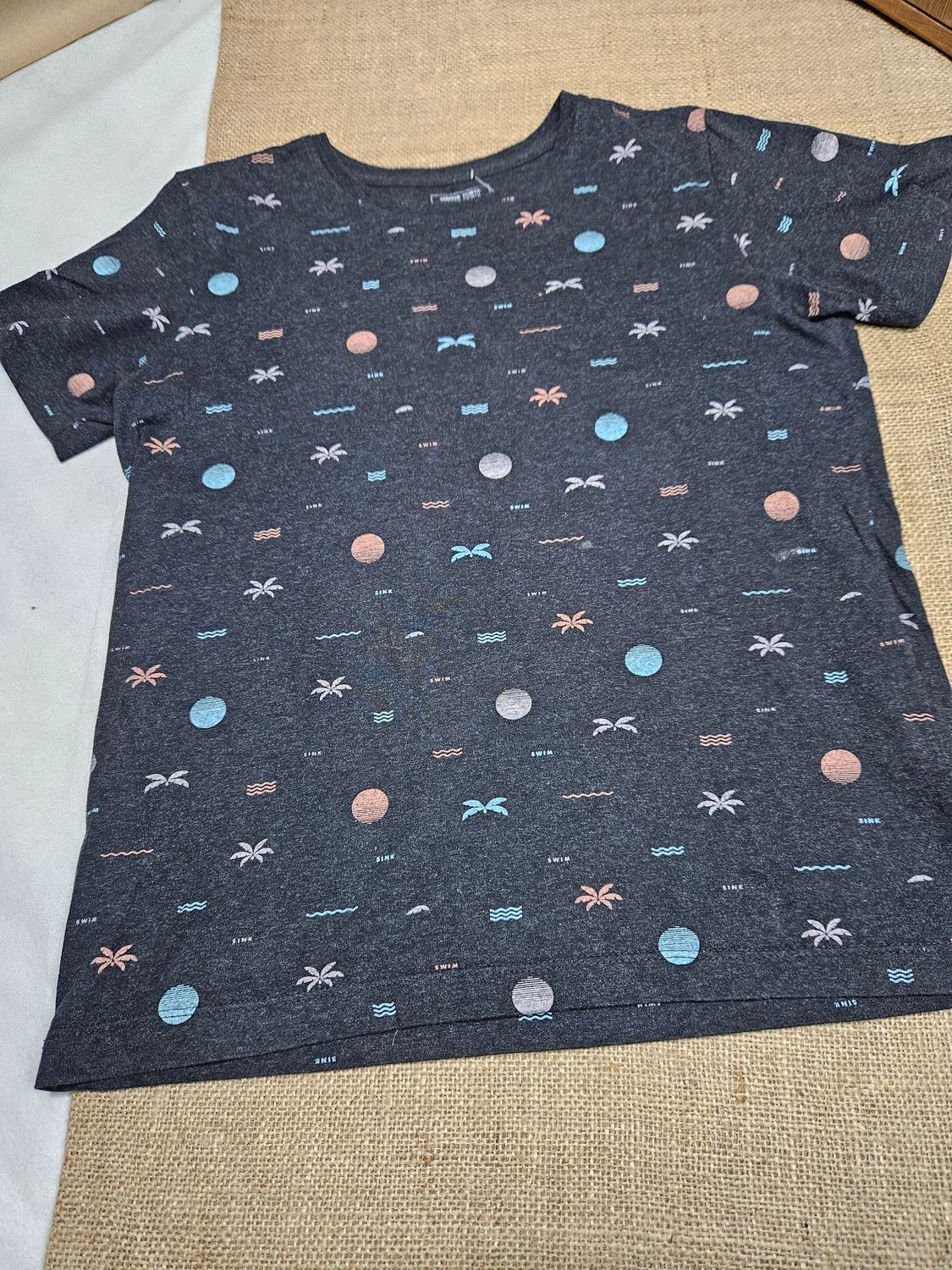REMERA DE ALGODÓN, MANGA CORTA, PARA NIÑO, MARCA FUZARKA, TALLE 13/14. GRIS CON PALMERAS Y OLAS