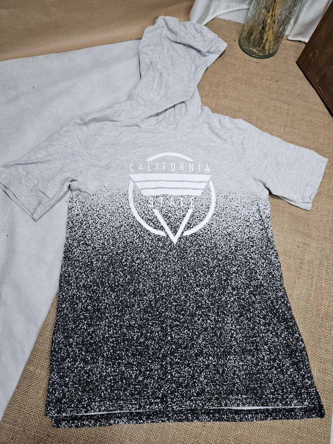 REMERA DE ALGODÓN, PARA NIÑO, MANGA CORTA, CON CAPUCHA. GRIS, CON DISEÑO CALIFORNIA. MARCA HYM. TALLE 10-12 - IGUAL A NUEVO