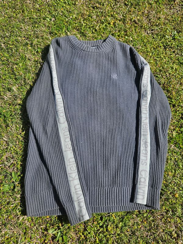 BUZO DE LANA, MANGA LARGA, CUELLO A LA BASE, COLOR VERDE MUSGO, MARCA CALVIN KLEIN. TALLE S - UNISEX