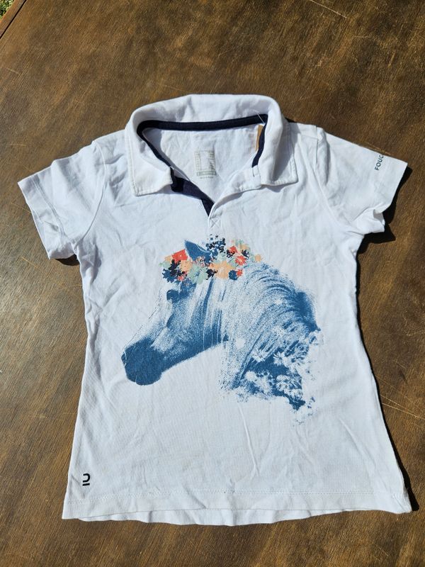 REMERA PARA NIÑA, EN ALGODÓN, CUELLO POLO. BLANCA CON DISEÑO DE CABALLO. MARCA DECATHLON. TALLE 6