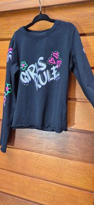 REMERA TOP PARA NIÑA, EN ALGODÓN, NEGRA, MANGA LARGA, CON ESTAMPA EN FRENTE Y MANGAS, EN PLATEADO Y BRILLOS. MARCA FUZARKA. TALLE 7/8. SIN USO