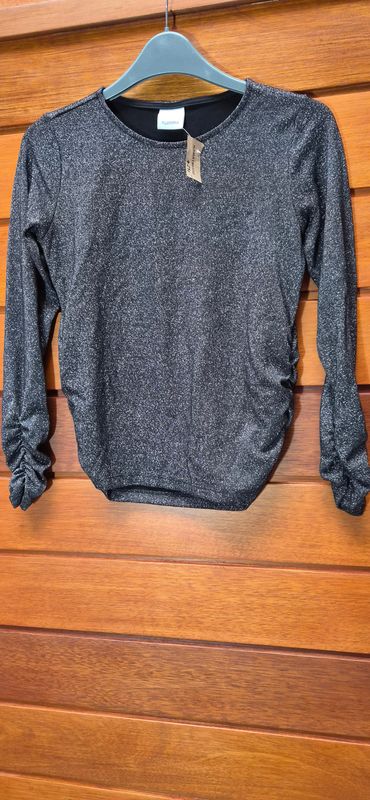 REMERA PARA NIÑA, EN LYCRA CON LUREX, MANGA LARGA, MANGAS Y LATERALES FRUNCIDOS. MARCA FUZARKA. TALLE 11/12