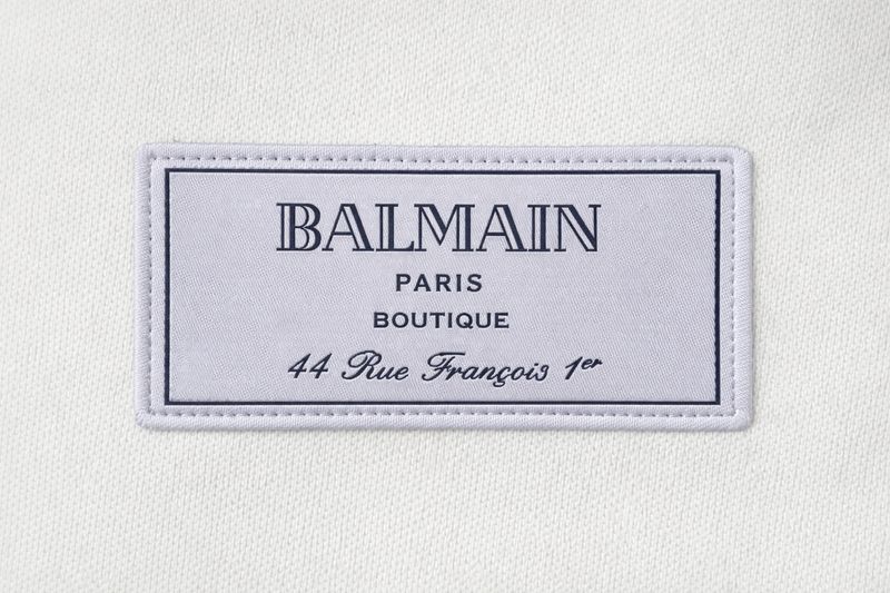 Close-up of Balmain Paris Boutique logo patch on luxury men’s white cotton T-shirt
