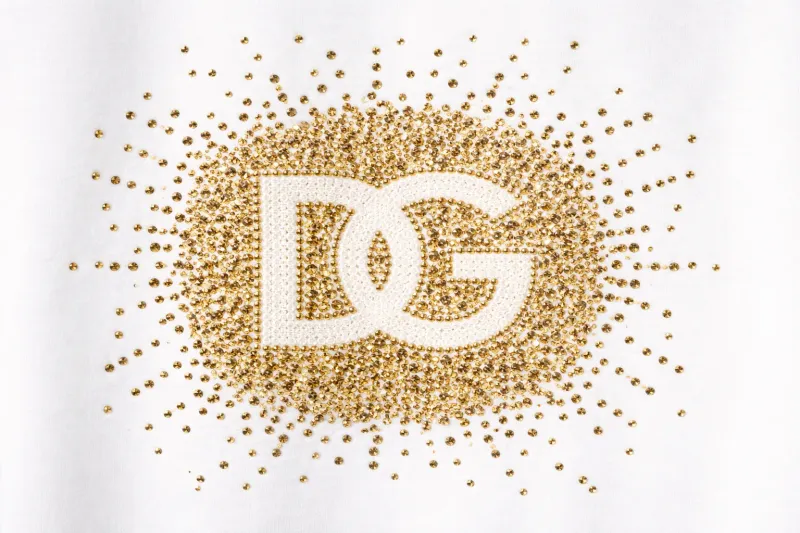 Dolce Gabbana gold stud DG logo close up detail on luxury white designer t shirt