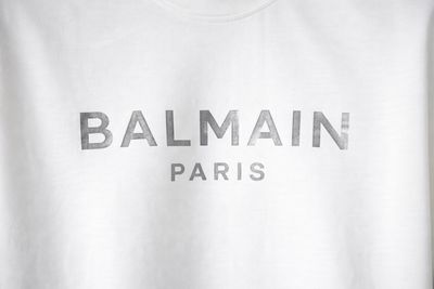 Close-up of Balmain Paris silver logo print on men’s white designer T-shirt