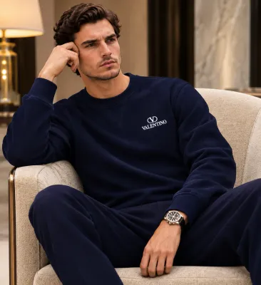Male model seated in a luxury lounge wearing a Valentino navy blue logo sweatshirt