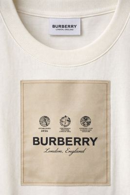 Burberry cream men's designer t-shirt close up featuring signature logo patch and premium cotton texture