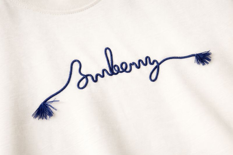 Burberry blue embroidered logo detail on cream luxury mens t shirt fabric close up