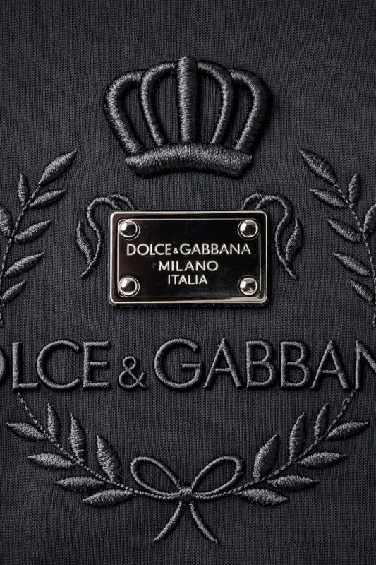 close up of dolce gabbana crown logo embossed black designer t shirt featuring milano italia metal plaque and luxury italian 