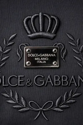 close up of dolce gabbana crown logo embossed black designer t shirt featuring milano italia metal plaque and luxury italian 