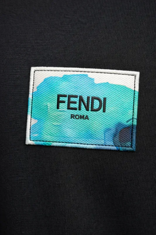 Close up of Fendi logo patch on black designer t shirt showing detailed fabric texture luxury mens tee