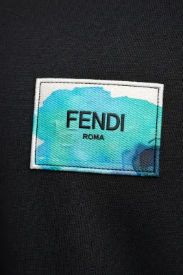 Close up of Fendi logo patch on black designer t shirt showing detailed fabric texture luxury mens tee
