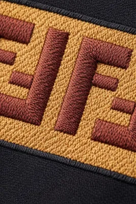 Close-up of Fendi embroidered FF logo detail on black luxury designer t-shirt fabric