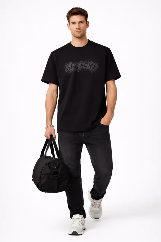 Male model walking in black Givenchy rhinestone designer mens tee holding sport bag