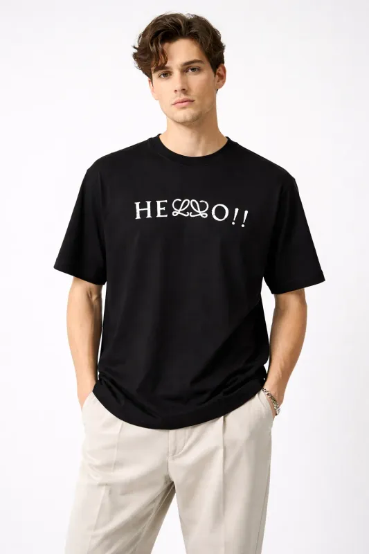 Male model wearing Loewe black hello print t-shirt front pose