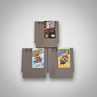 Stack of three Mario Bros NES game cartridges on a white background