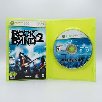 Open green Xbox 360 case for Rock Band 2 displaying the game disc and manual