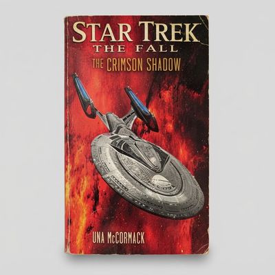 Front cover of the Star Trek: The Fall "The Crimson Shadow" paperback featuring a starship against a red nebula background