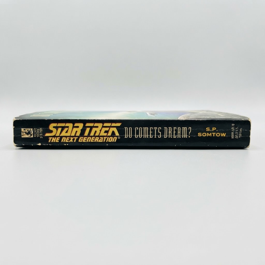 The spine of the Star Trek: TNG "Do Comets Dream?" vintage paperback in black with gold text and minor edge wear