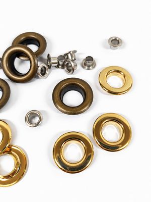 Flat or domed eyelets with brass washers for leather goods and garment making.