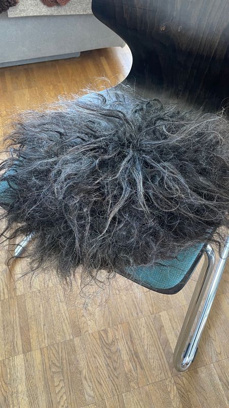 Sitzkissen "Steinschaf" mit mittellangen fast ganz schwarzen glänzenden Haaren.