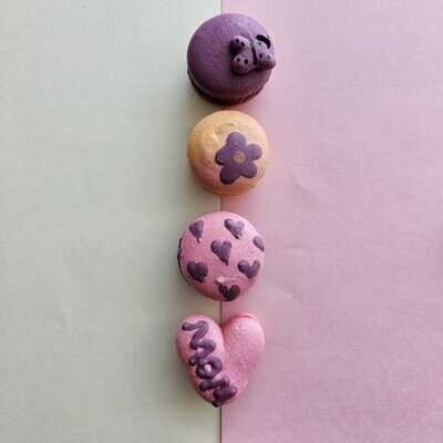 Macarons in a vertical line with a butterfly, flower and hearts and the word mom on the heart macaron